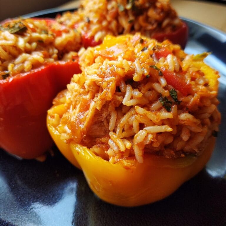 Close-up of Halloween Gefüllte Paprika mit Huhn und Reis (stuffed peppers with chicken and rice) on a dark plate.