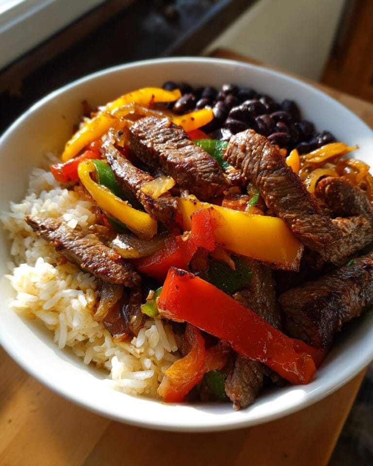Close-up of a High-Protein Steak-Fajita-Bowl with rice, steak, peppers, onions, and black beans.