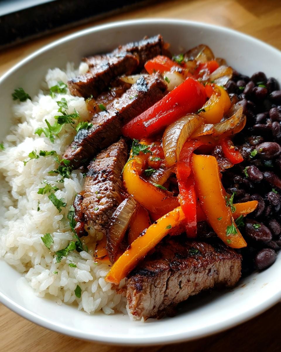 A vibrant High-Protein Steak-Fajita-Bowl with sliced steak, rice, beans, and sautéed peppers and onions.