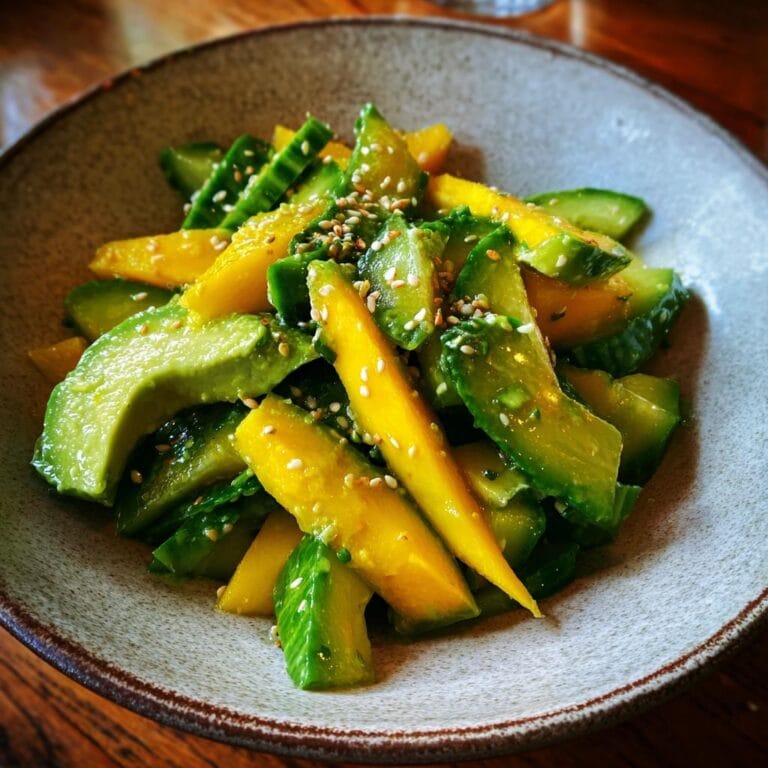 Nahaufnahme von Mango-Gurken-Salat mit Avocado, dekoriert mit Sesamsamen.