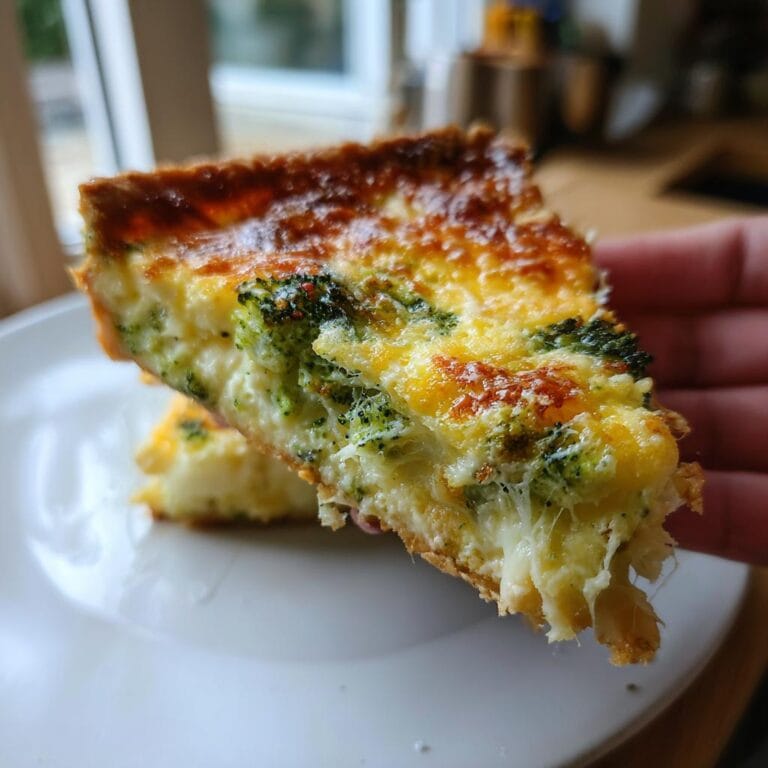 A delicious slice of Quiche mit Brokkoli und Käse, showcasing the cheesy filling and broccoli.