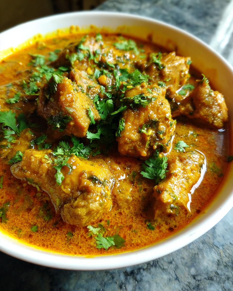 Bowl of Afrikanisches Kokos-Hähnchen-Curry garnished with fresh cilantro.