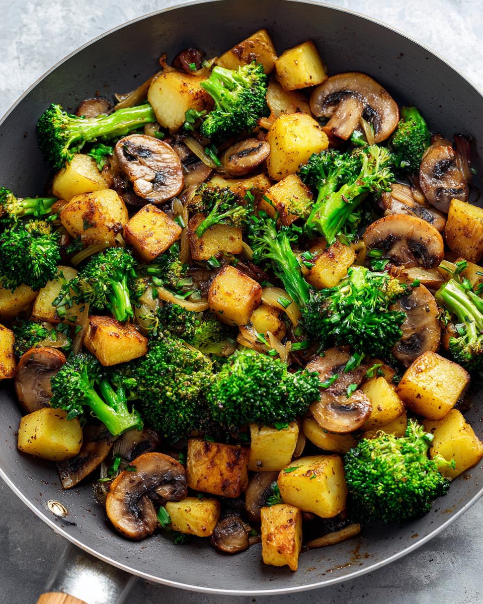 Close-up of Brokkoli Kartoffel Pfanne mit Pilzen in a pan, showcasing potatoes, broccoli, and mushrooms.