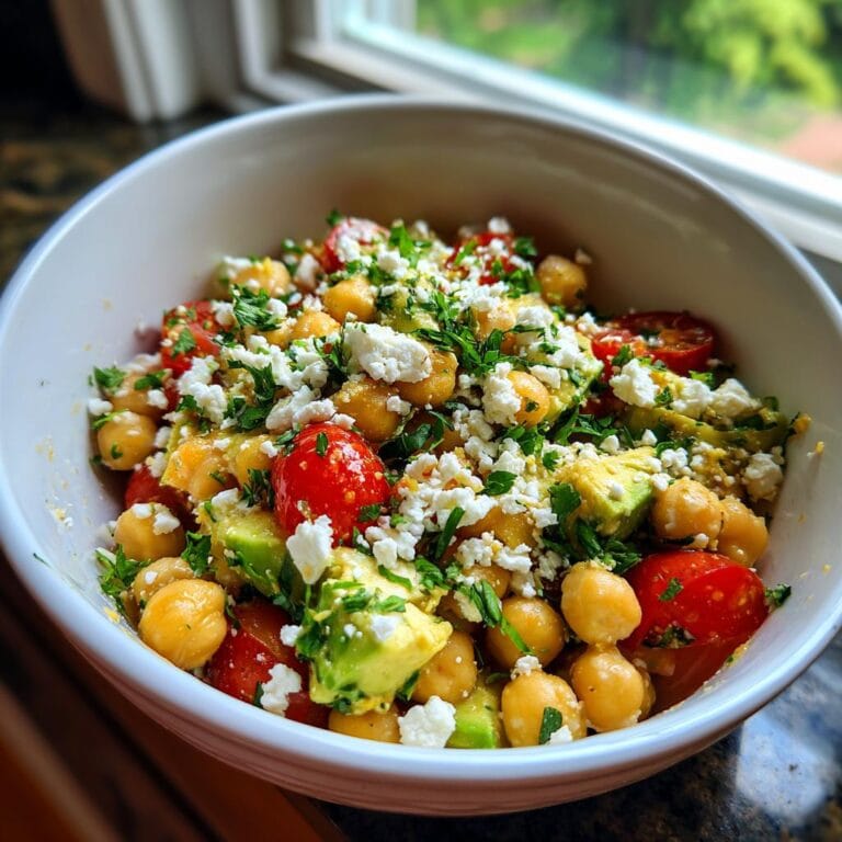 A colorful bowl of Chickpea Feta Avocado Salad with tomatoes and parsley.