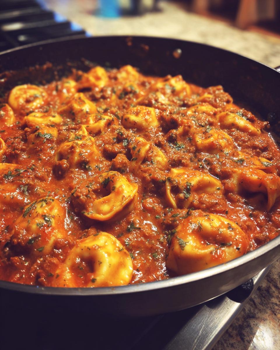Nahaufnahme einer Cremige Tortellini-Pfanne mit würzigem Hack, serviert in einer schwarzen Pfanne.