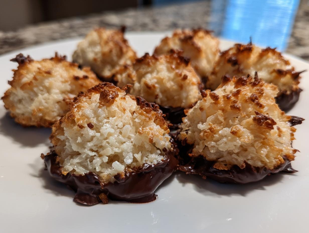 Close-up of homemade Haselnussmakronen Rezept dipped in chocolate on a white plate.