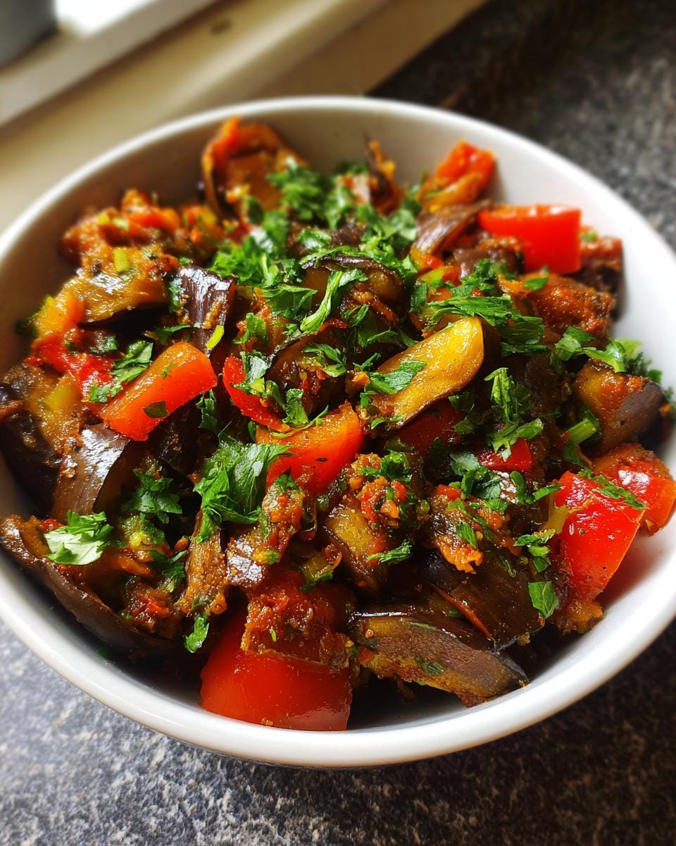 Close-up of Orientalische Auberginenpfanne mit Gewürzen, a vegan dish with eggplant, peppers, and herbs.