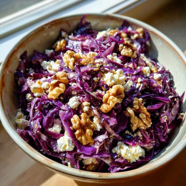 A bowl of vibrant Rotkohl Feta Salat topped with walnuts, ready to enjoy.