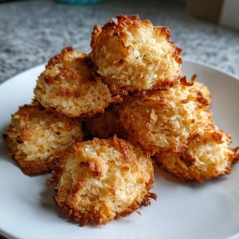 A pile of golden brown Saftige Nussmakronen on a white plate, ready to eat.
