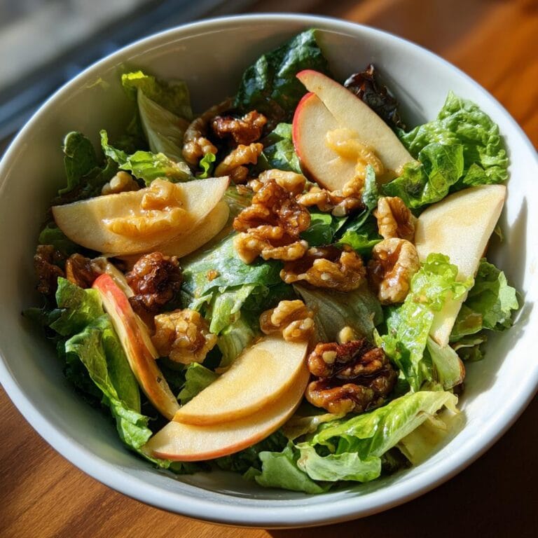 A bowl of Salat mit Apfel und karamellisierten Walnüssen, featuring lettuce, apple slices, and caramelized walnuts.