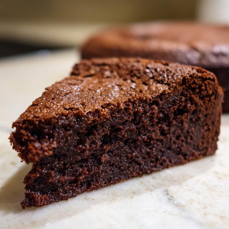 A slice of Bestes Schokokuchen Rezept, showcasing its moist texture and rich chocolate color.