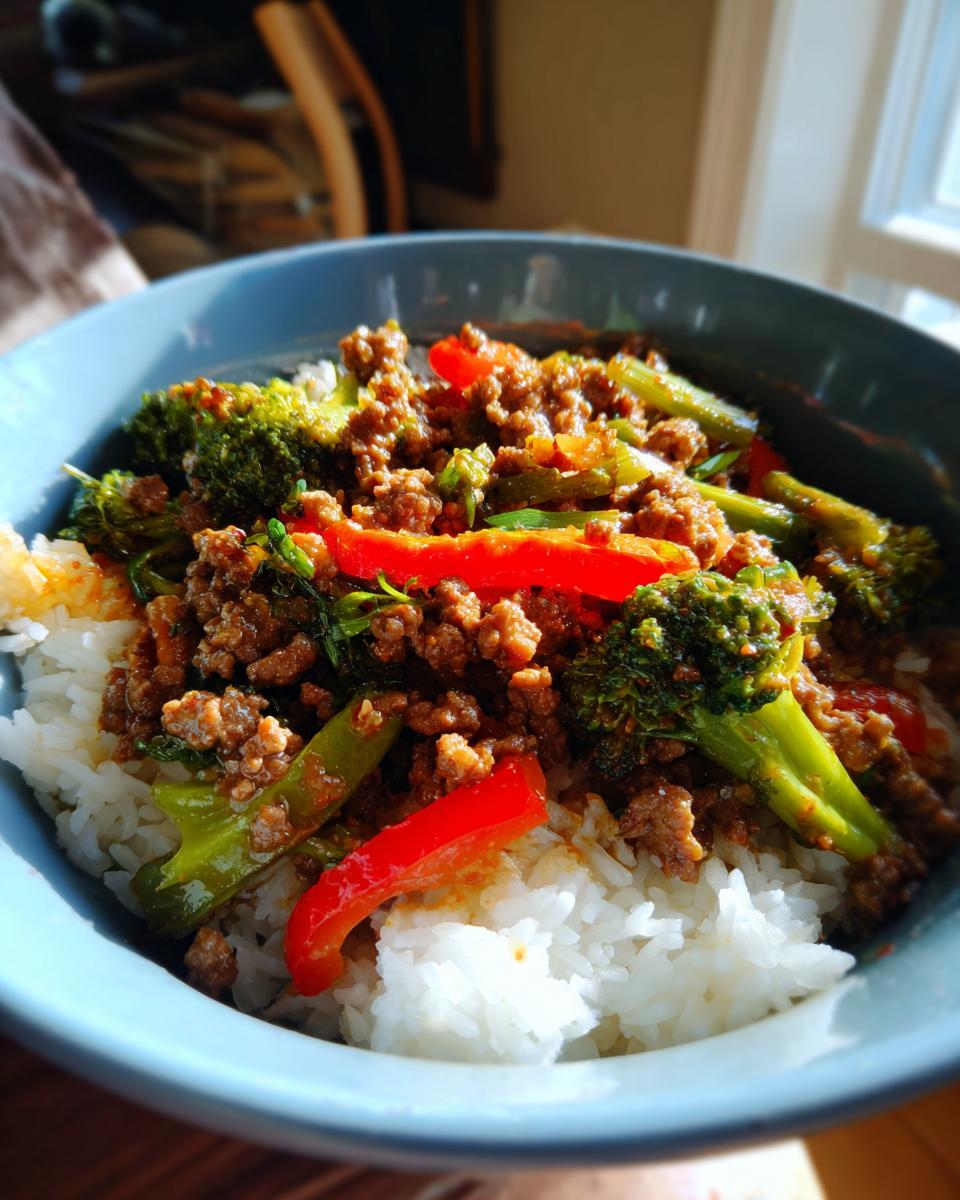A bowl of Spicy Ground Beef Stir-Fry Bowl with Garlic Veggies & Steamy Rice, featuring broccoli and red peppers.