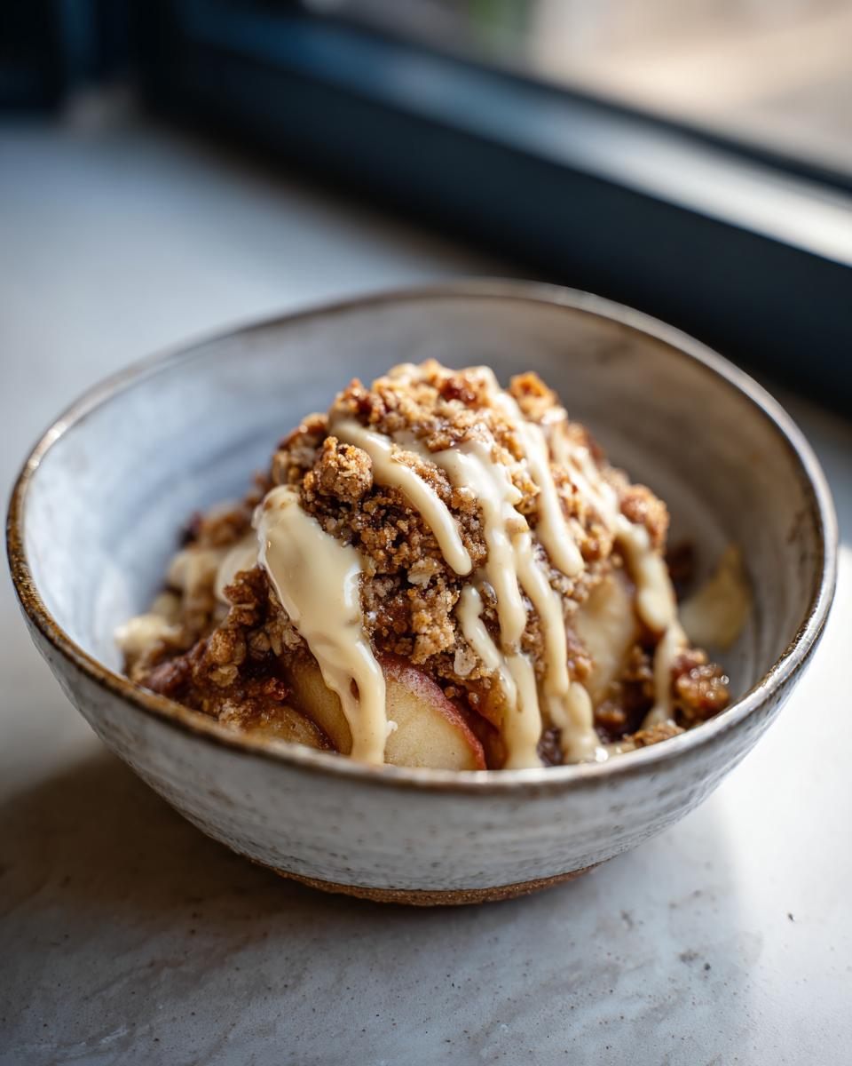 Eine Schüssel mit Bratapfel Crumble, garniert mit Zimtcreme, ein köstliches deutsches Dessert.