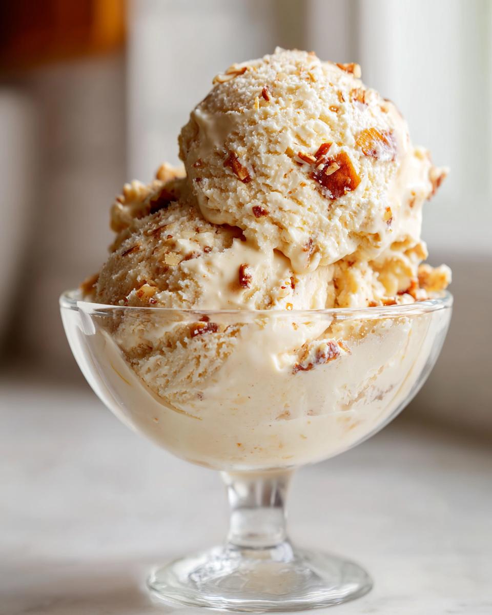 Close-up of creamy Gebrannte Mandel Eis with caramelized almonds in a glass bowl.
