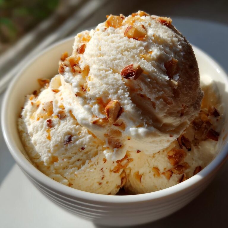 Nahaufnahme einer Schüssel mit cremigem Gebrannte Mandel Eis, bestreut mit gehackten Mandeln.