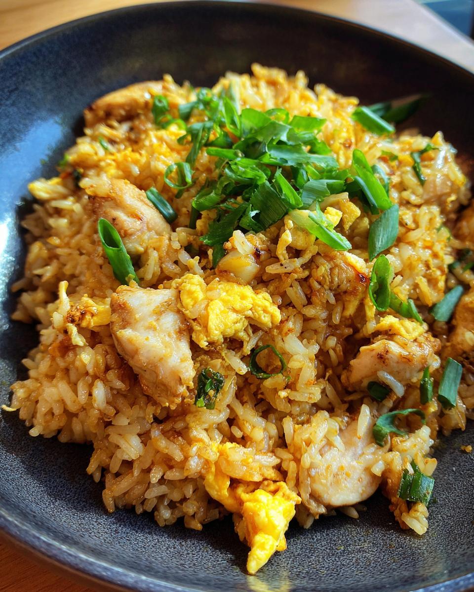 Nahaufnahme von Gebratenem Reis mit Huhn und Ei, garniert mit Frühlingszwiebeln.