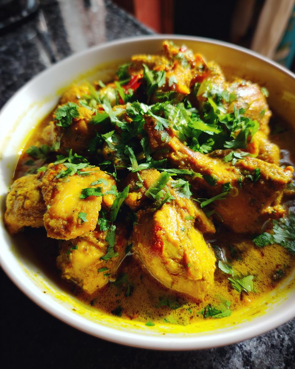 Nahaufnahme eines dampfenden Hähnchencurrys mit viel Soße und frischer Petersilie garniert. Ein Gericht aus Rezepte mit Fleisch.