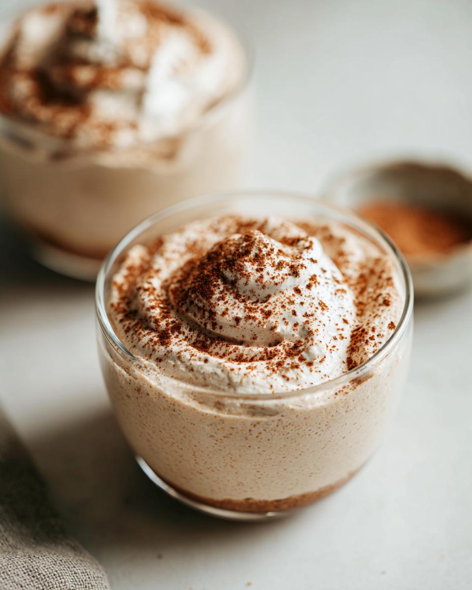Serviert in einem Glas: cremige Weiße Lebkuchen-Mousse mit weißer Schokolade, bestäubt mit Zimt.