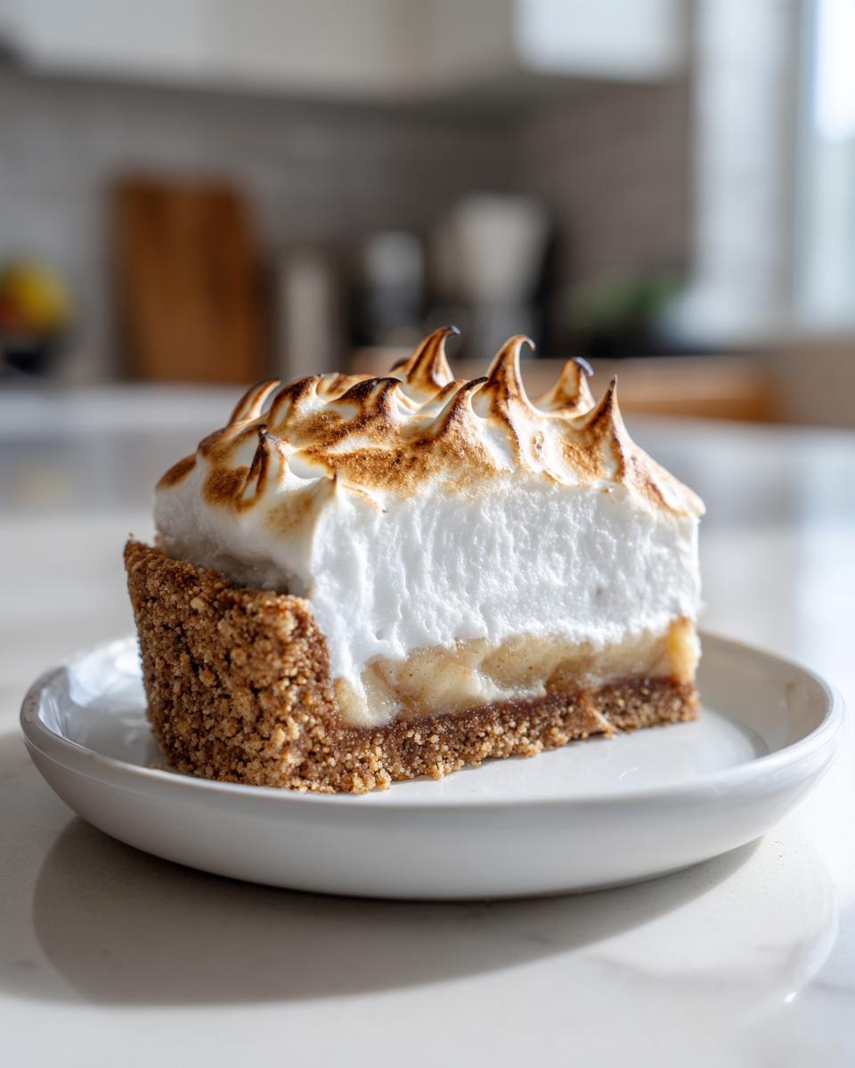 Ein Anschnitt von Nach diesem Apfel-Baiser-Torte mit knusprigem Boden und goldbraun getoastetem Baiser.