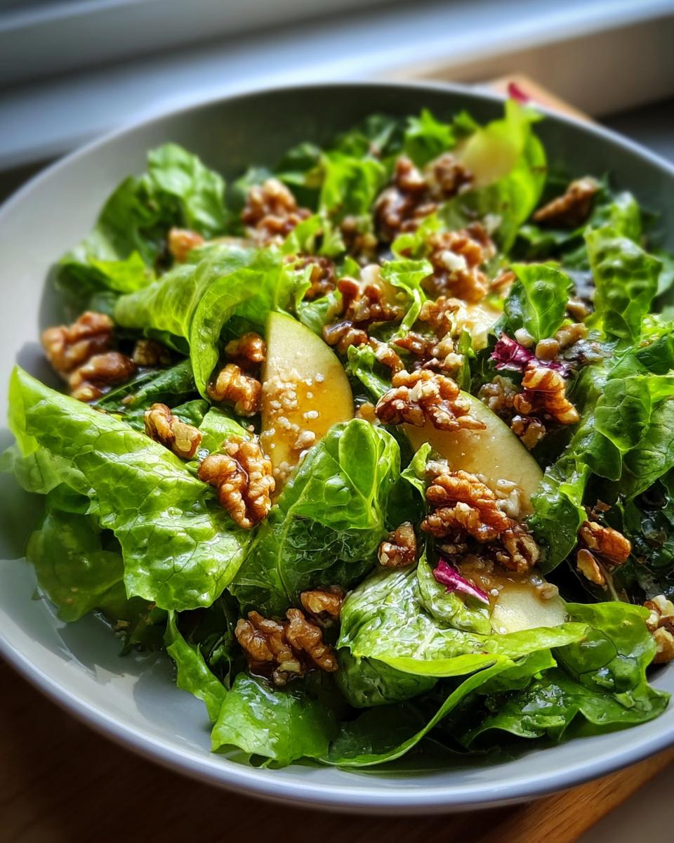 Nahaufnahme eines Grüner Salat mit Walnuss-Topping, garniert mit Birnenspalten und Dressing.