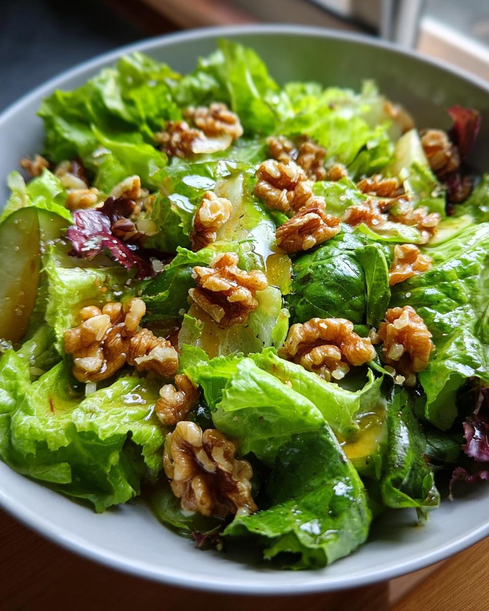 Nahaufnahme eines Schüssel mit frischem Grüner Salat mit Walnuss-Topping und leichtem Dressing.