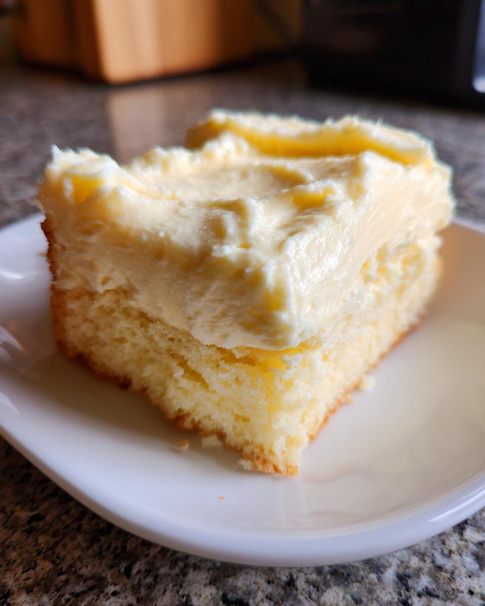 Nahaufnahme eines Stücks Rahmkuchen Rezept Der Immer Gelingt mit dicker, cremiger heller Auflage auf einem weißen Teller.