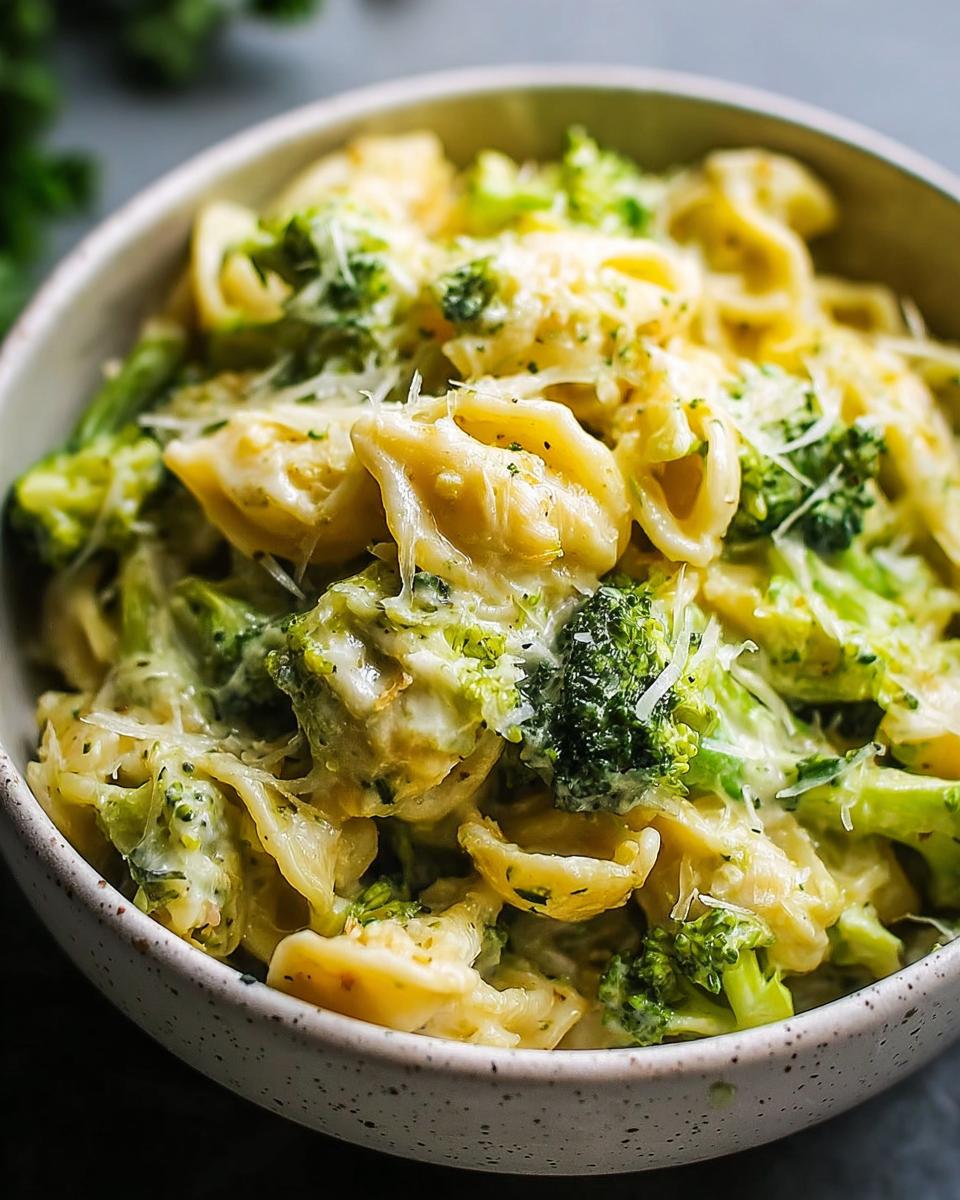 Nahaufnahme einer Schüssel mit cremiger Käsige Brokkoli-Nudelpfanne, garniert mit geriebenem Käse.