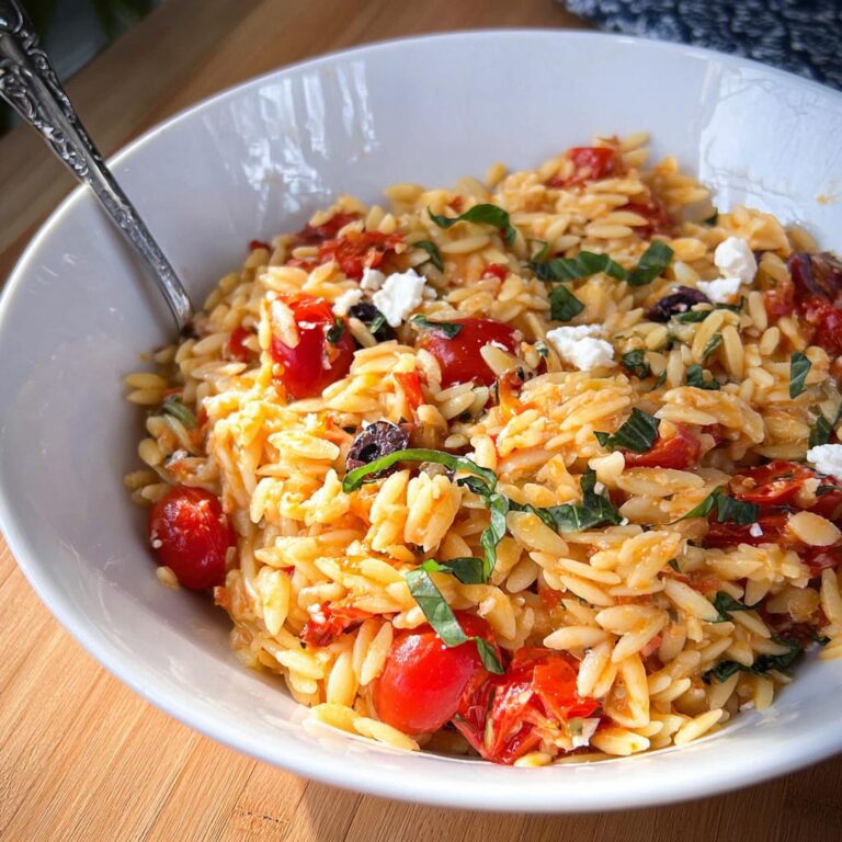 Nahaufnahme von One-Pot-Orzo mit Tomaten & Basilikum, garniert mit Feta und frischem Basilikum.