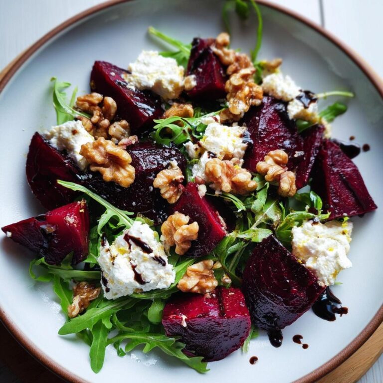 Nahaufnahme eines Rote-Bete-Salat mit Ziegenkäse, Walnüssen und Rucola, beträufelt mit Balsamico-Glasur.