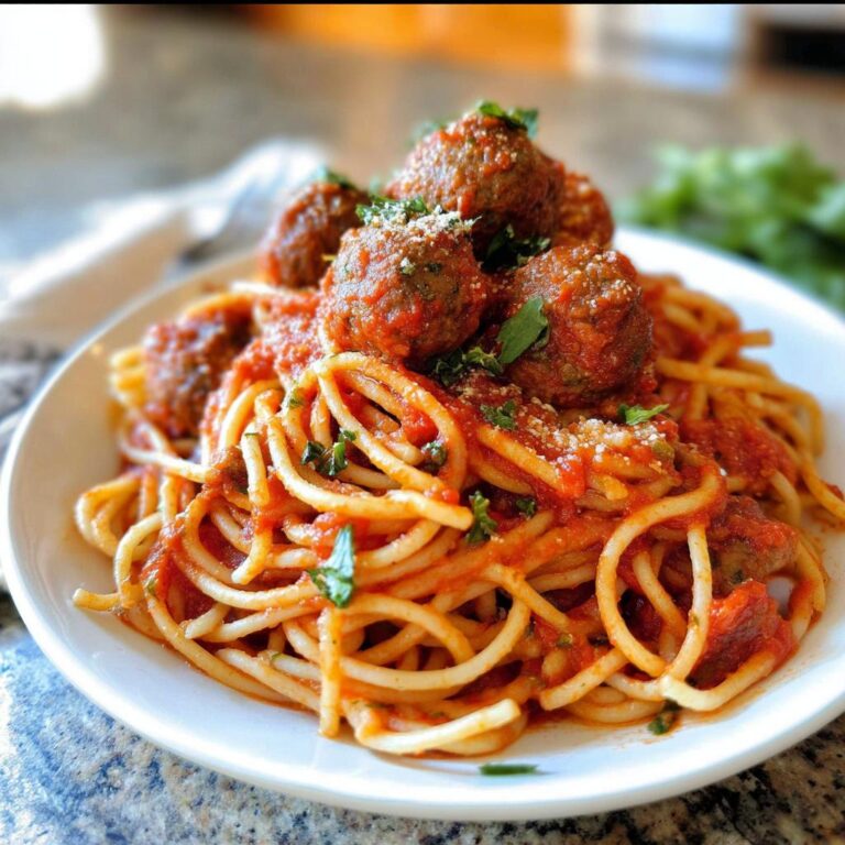 Teller mit Spaghetti mit Fleischbällchen, bedeckt mit Tomatensauce und Parmesan.