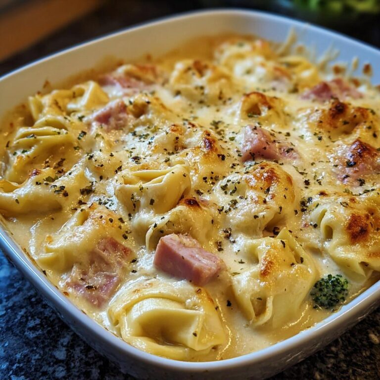 Nahaufnahme eines cremigen Tortellini-Auflauf mit Schinken und Käse, goldbraun überbacken.